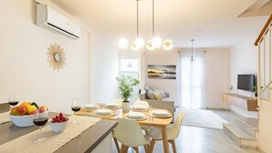 A modern dining area with a long table set for four, a fruit bowl, and a wine glass on the counter. - 3 BD house with Private Solarium and patio (Cordoba)