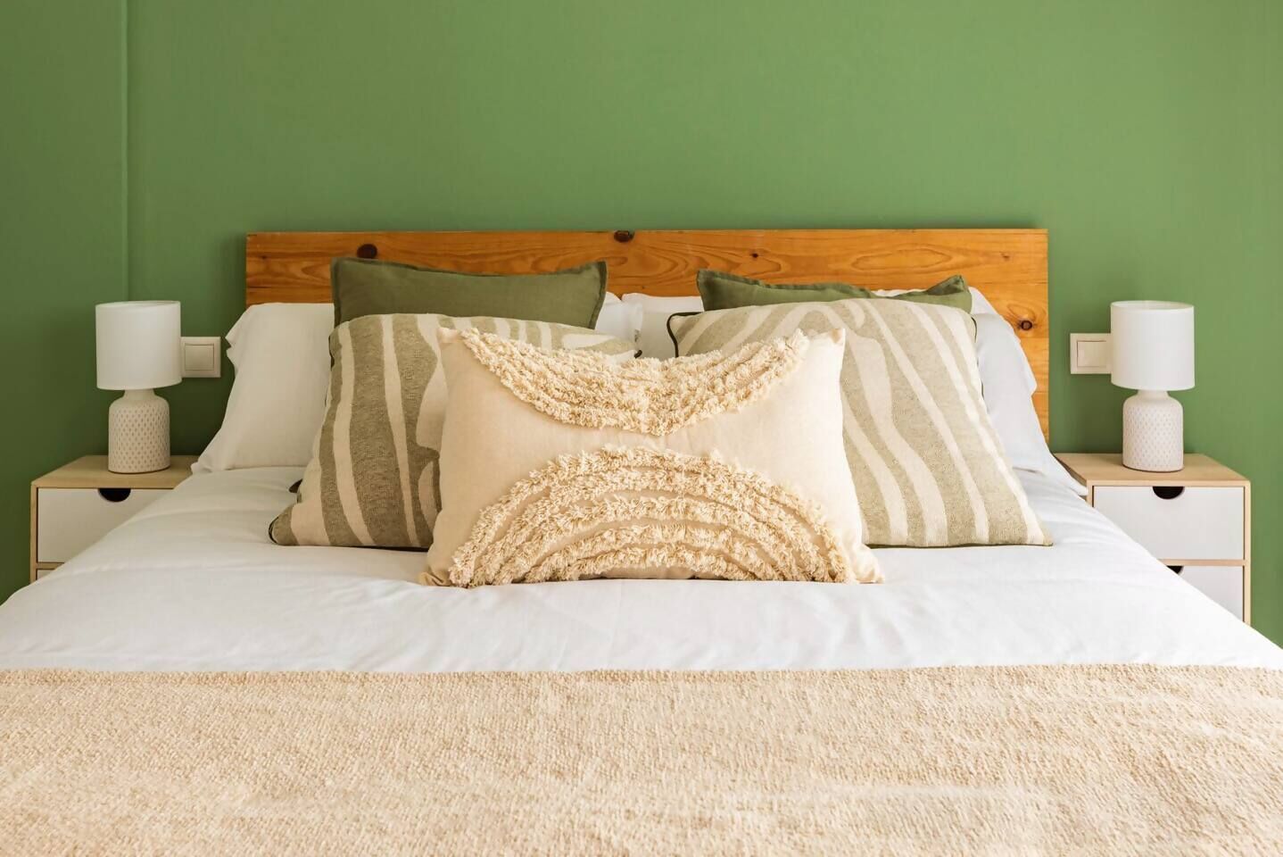 A bed with a wooden headboard, multiple pillows, and two bedside tables with lamps.