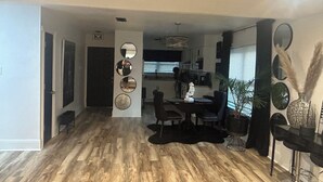 A spacious living area with a wooden floor, a dining table with chairs, a black rug, and a large mirror on the wall. - Charming 3-bedroom house in LaPlace with AC, WiFi (LaPlace)