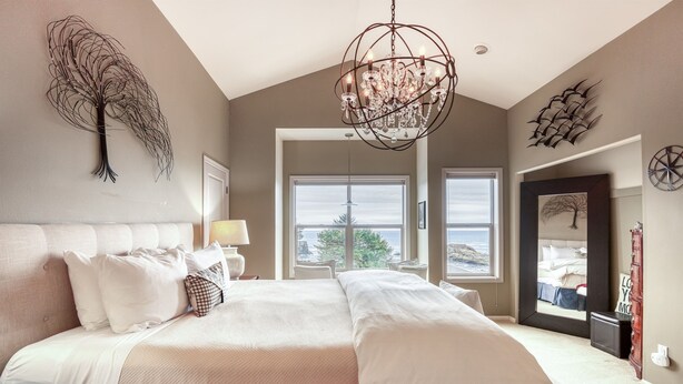 Ein geräumiges Schlafzimmer mit einem großen Bett, einer Chandelier und Blick ins Freie durch ein Fenster.