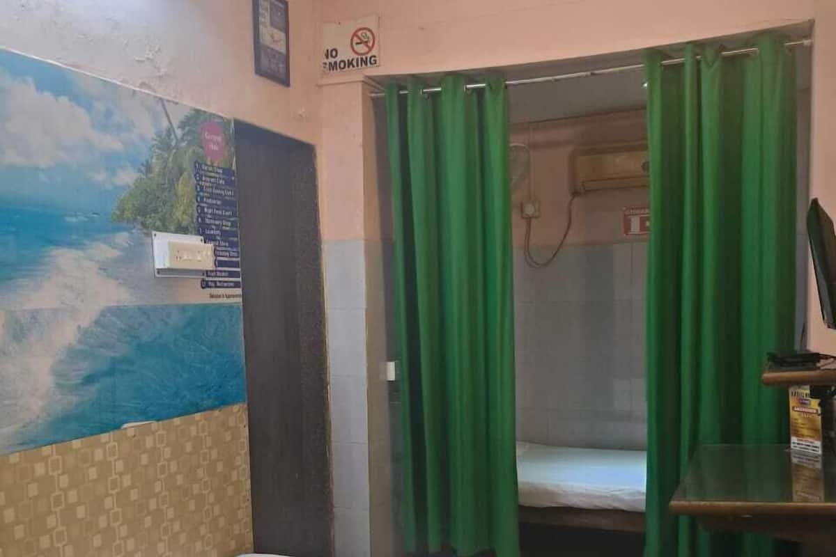 Una camera d'albergo con un letto, un tavolino, una tenda verde e un cartello che indica il divieto di fumare.