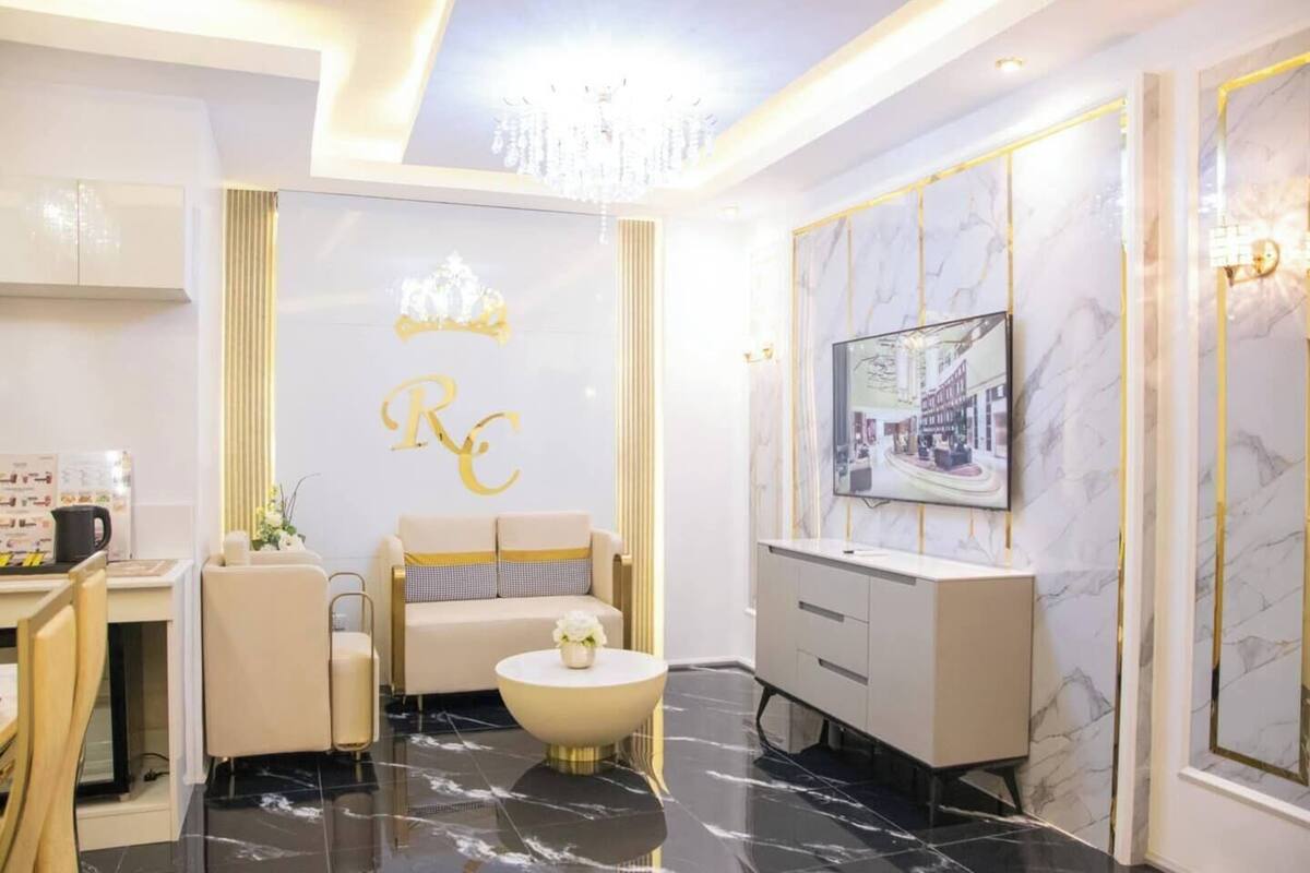 Une chambre d’hôtel moderne avec un sol en marbre, un canapé, une table basse, un téléviseur et un lustre.