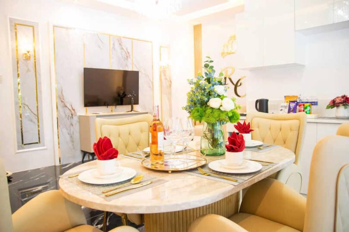 Un coin repas comprenant une table ronde, des chaises, un téléviseur et un vase décoratif avec des fleurs.