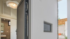 Un intérieur moderne avec une porte coulissante donnant sur une salle de bain, un spot encastré au plafond et une petite fenêtre offrant une vue sur l’extérieur.