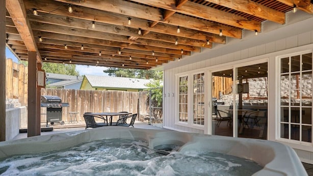 A hot tub under a wooden pergola with a table and chairs nearby. - Desert Dreams Retreat Hot Tub Game Room Fire Pit (Sparks)
