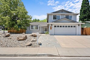 A two-story house with a garage, a driveway, and a landscaped front yard with rocks and a tree. - Desert Dreams Retreat Hot Tub Game Room Fire Pit (Sparks)