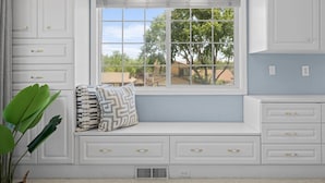 A room with a built-in bench, white cabinetry with gold handles, and a window with a view of trees and houses. - Desert Dreams Retreat Hot Tub Game Room Fire Pit (Sparks)