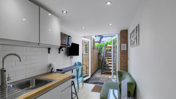 A modern kitchen with a built-in sink, a wooden countertop, and a TV mounted on the wall. - Ecclesall Road Apartment (Sheffield)