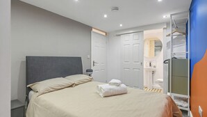 A bedroom with a bed, a bedside table, a wardrobe, and a bathroom visible through an open door. - Ecclesall Road Apartment (Sheffield)