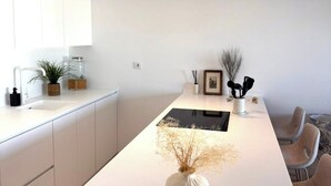 Een moderne keuken met een gebogen kookeiland, witte kasten en een centraal geplaatste vaas.