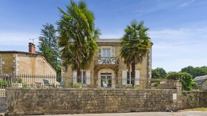 A stone building with a central entrance, surrounded by a stone wall and palm trees.