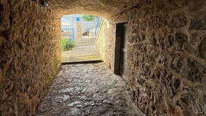 Ein schmaler Steinweg, der zu einem offenen Bereich mit Stufen und Blick ins Grüne führt.