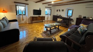 Ein Wohnzimmer mit Holzböden, einer Couch, einem Couchtisch und einem Fernseher.