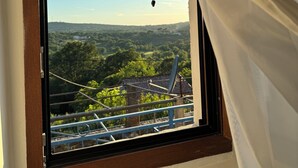 Ein Fenster mit Blick auf eine ländliche Landschaft, Bäume und ein Gebäude in der Ferne.