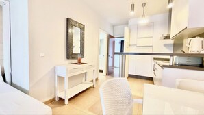A modern, well-lit room with a white sofa, a small white table, and a decorative mirror on the wall. - Studio in front of the pool (Marbella)