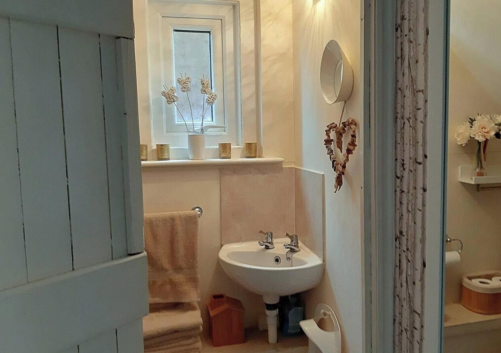 Une salle de bain avec un lavabo, un miroir et une fenêtre.