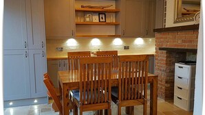 A kitchen with a dining table, chairs, and a brick fireplace. - Charming Villa in Ryde - Child Friendly (Ryde)
