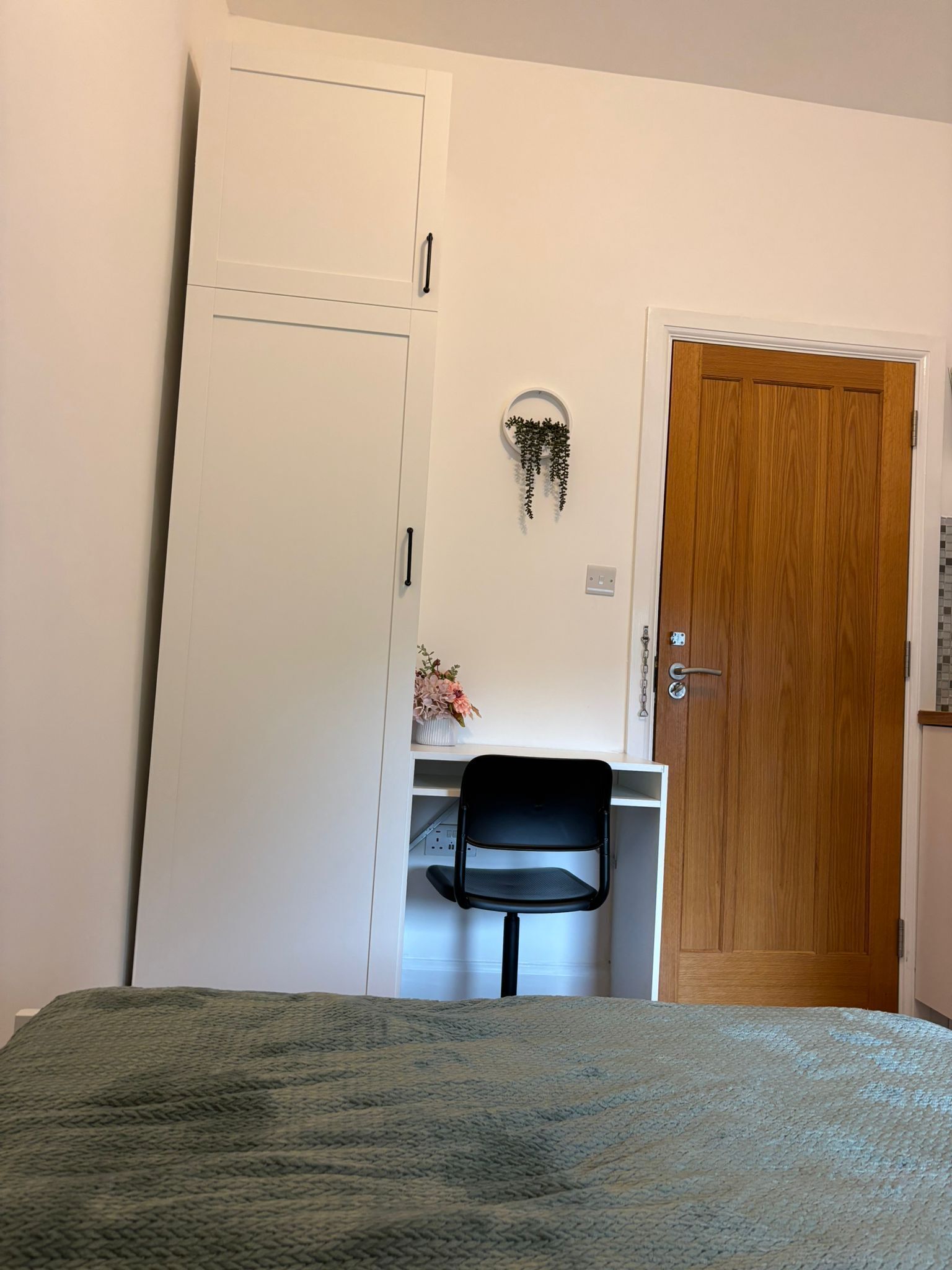 Une chambre à coucher avec un lit, un bureau et une chaise, une armoire et une porte.