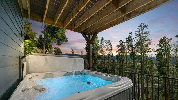 Ein Whirlpool auf einer Holzterrasse mit Blick auf Bäume und Berge.