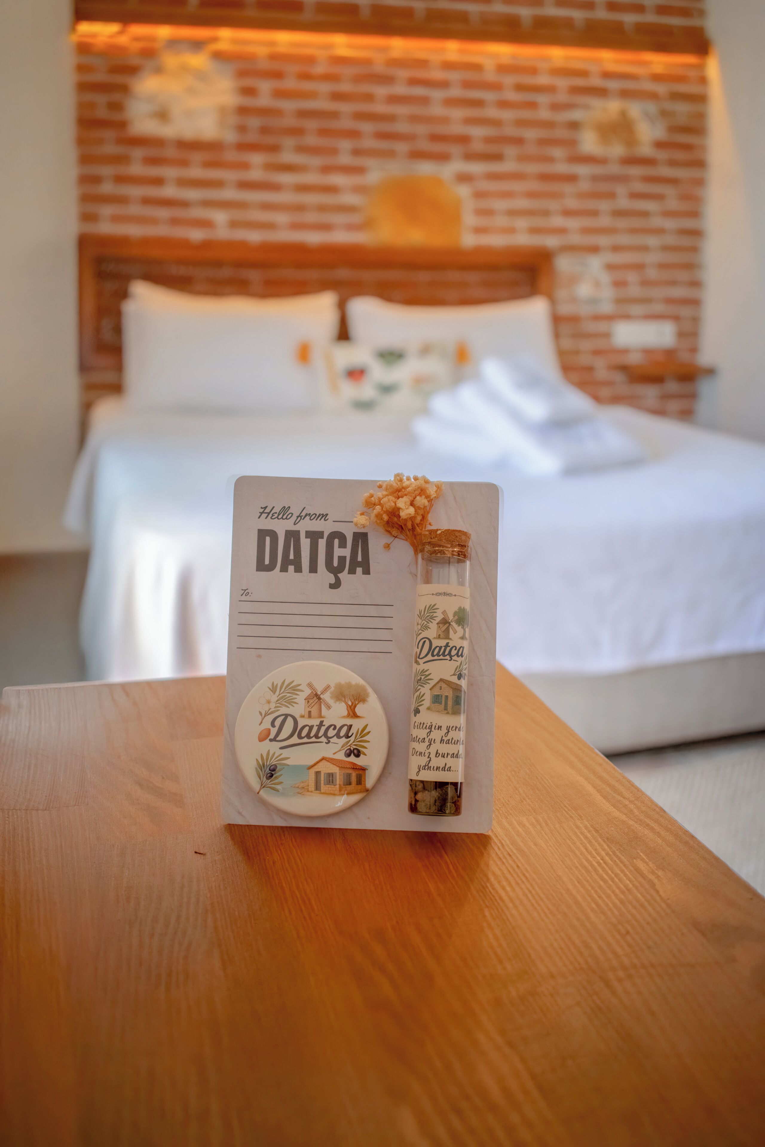 A wooden table with a welcome card and a bottle of Datca wine.