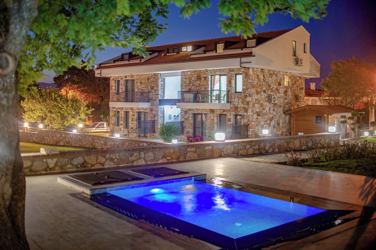 A modern two-story stone building with a swimming pool in the foreground.