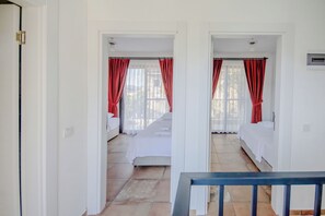 A hotel room with two beds, a view of the outside, and a staircase leading to another room.