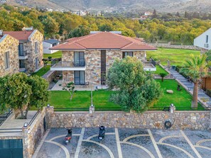 A modern two-story house with a stone facade, a tiled roof, and a well-maintained lawn.