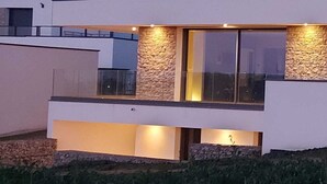 A modern two-story house with a stone facade, large windows, and a balcony. - Maison vue de mer Pléneuf Val André near coastal paths and beaches (Pléneuf-Val-André)