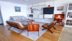 A modern living room with a sofa, two leather chairs, a coffee table, and a TV mounted on the wall. - Atlantis Ocean front (Vila Nova de Gaia)