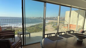 A balcony with a view of the ocean and cityscape, furnished with a table and chairs. - Atlantis Ocean front (Vila Nova de Gaia)