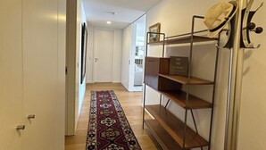 A hallway with a patterned rug, a metal shelf unit, and a hat rack. - Atlantis Ocean front (Vila Nova de Gaia)