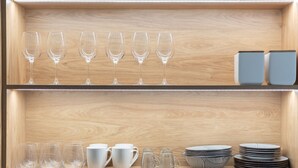 Une étagère en bois avec des verres à vin et des bols.