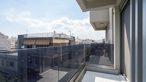 Un balcon doté d’une balustrade en verre donnant sur un paysage urbain.
