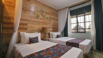 A room with two beds, wooden walls, a window with bars, and a view of a building outside.