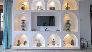 A wall with multiple arched niches displaying decorative items, a television, and a power outlet. - Aqueduct 1359 Hotel Apartments (Kampala)