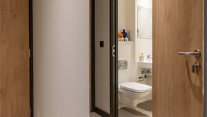 A modern bathroom with a toilet, sink, and storage shelves. - Student Only Port on the Square (Bristol)