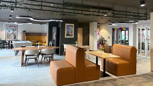 A modern interior with a seating area featuring orange leather sofas and a wooden table. - Student Only Port on the Square (Bristol)