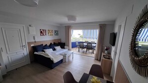 Una habitación de hotel moderna con una cama, un área de comedor y un televisor.
