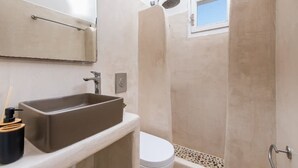 A bathroom with a rectangular sink, a toilet, and a shower area. - Golden Sunrise Suites - Santorini Lux Family Suite (Santorini)
