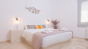 Un dormitorio con una cama grande, dos mesitas de noche, luces fijadas en la pared y un adorno mural.