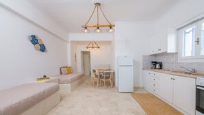Una cocina compacta con armarios blancos, horno integrado, cafetera y comedor con mesa y sillas.