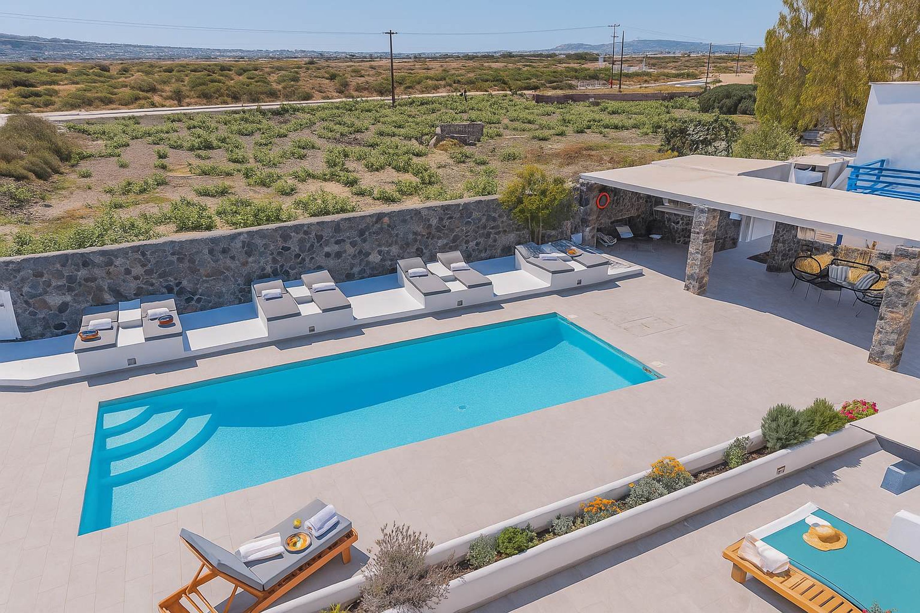 A modern outdoor pool area with lounge chairs and a stone wall.