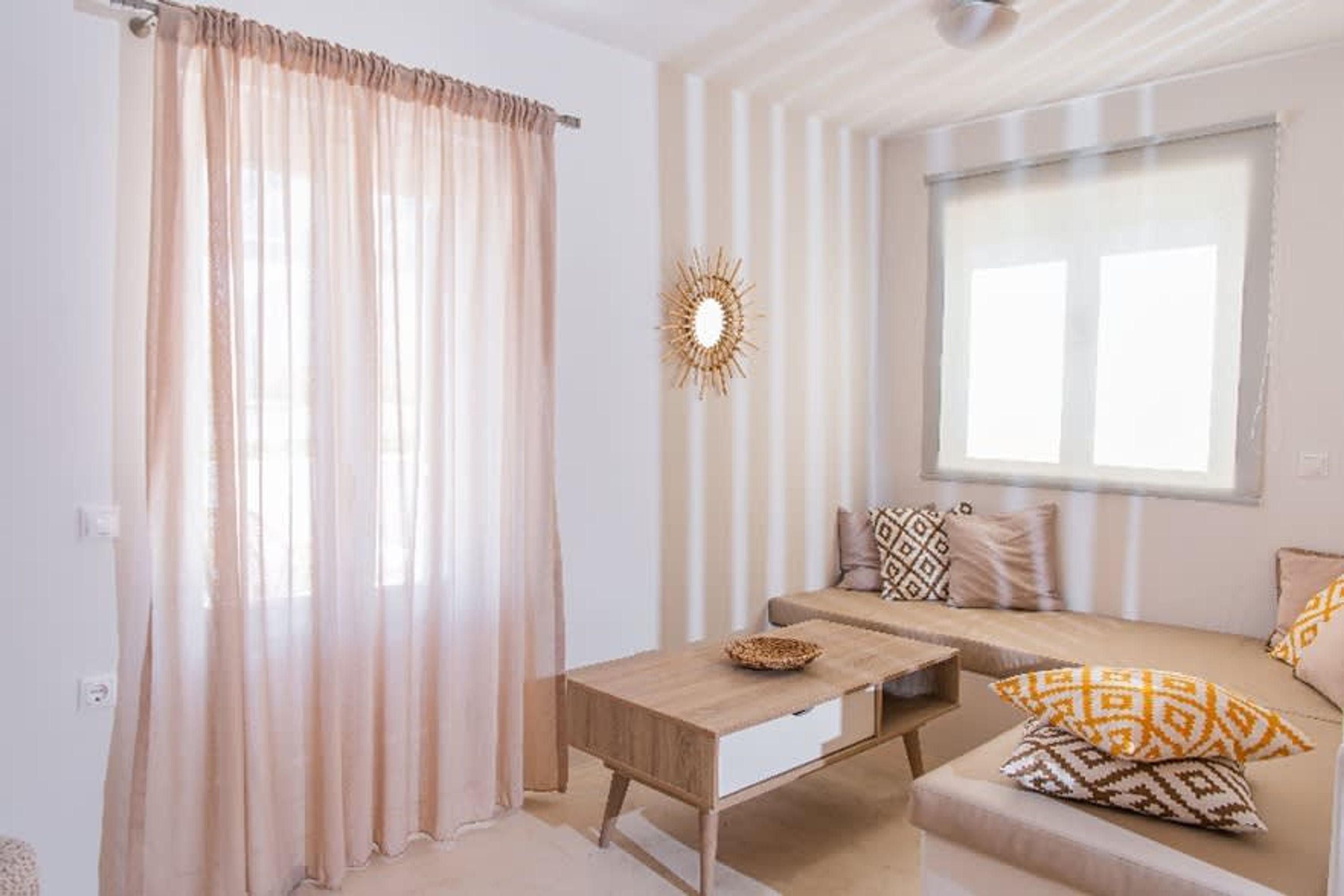 A room with a sofa, a coffee table, and a window with curtains.