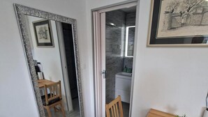 A room with a dining table, chairs, a mirror, a framed picture, and a small potted plant.