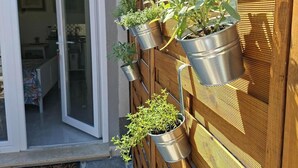 A vertical garden with various plants in metal pots against a wooden fence.