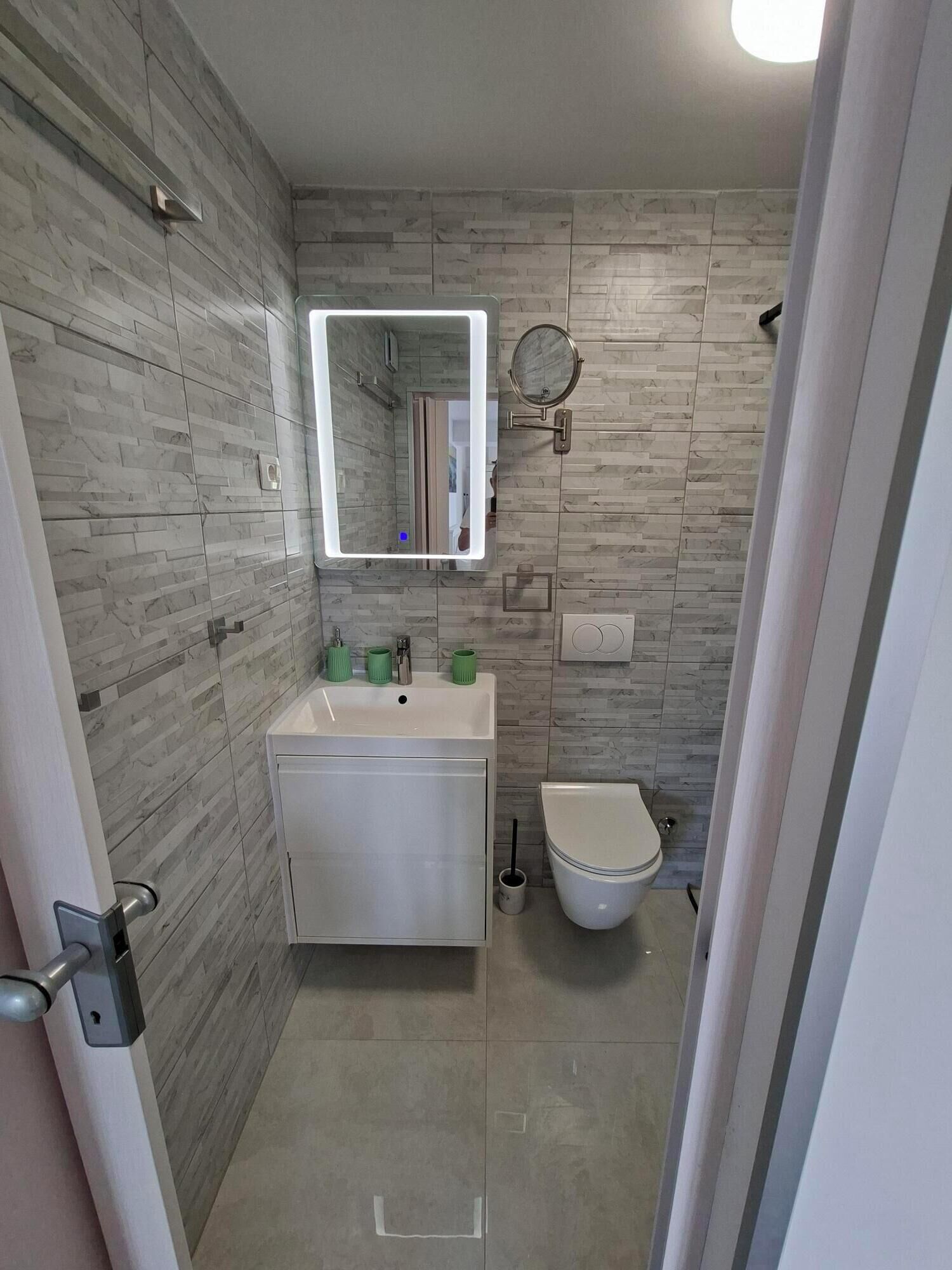 Un baño de diseño moderno, con un espejo grande, un lavabo con tazas verdes y un inodoro.