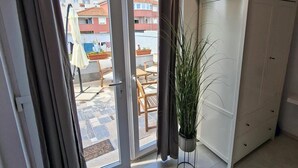 A room with a sliding glass door leading to an outdoor area with a table and chairs, a potted plant, and a white wardrobe.