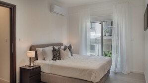 A modern bedroom with a bed, bedside table, and a view of the outdoors. - Phaedrus Living: Travertine Residences 101 (Strovolos)