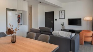 A modern living room with a sofa, a dining table, and a TV. - Phaedrus Living: Travertine Residences 101 (Strovolos)
