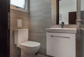A modern bathroom with a toilet, sink, and mirror. - Phaedrus Living: Travertine Residences 101 (Strovolos)